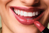 Geschminkte Lippen werden gezeigt, wobei ein Lippenstift vor das Gesicht gehalten wird