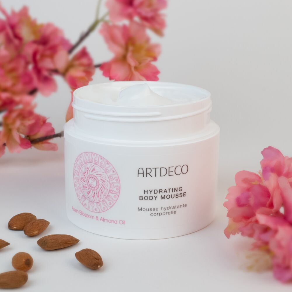 Produktbild des Hydrating Body Mousse, welches umgeben von Kirschblüten und Mandeln ist