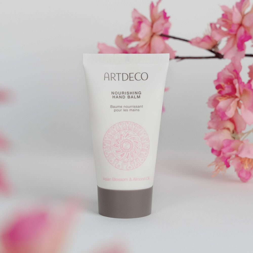Produktbild des Nourishing Hand Balm, welches umgeben von Kirschblüten ist