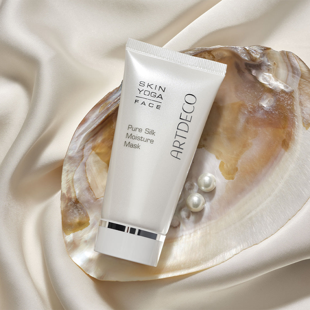Pure Silk Moisture Mask liegt in einer Muschel auf einem hellen. seidenen Hintergrund