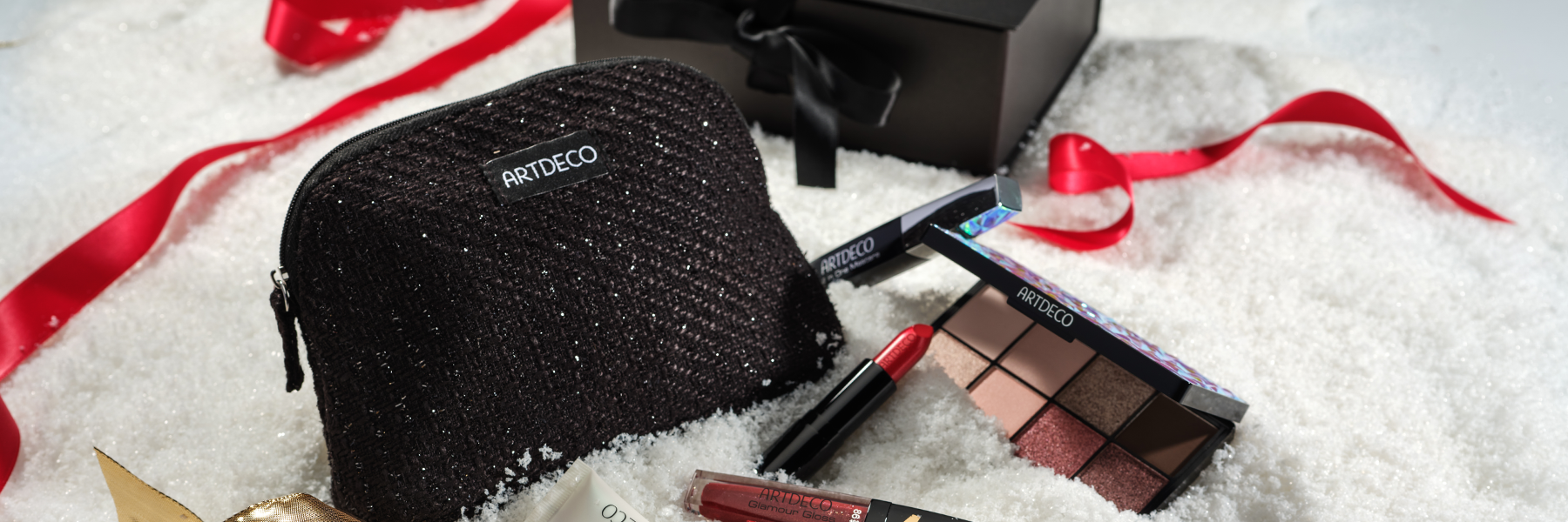 Mood-Bild mit einer Kosmetik Tasche und der ARTDECO Box im Schnee umgebenen von verschiedenen Make-up Produkten
