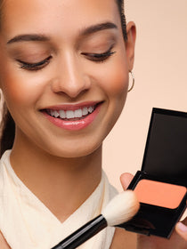 Model nimmt mit einem Blusher Brush Pigmente eines Blusher auf