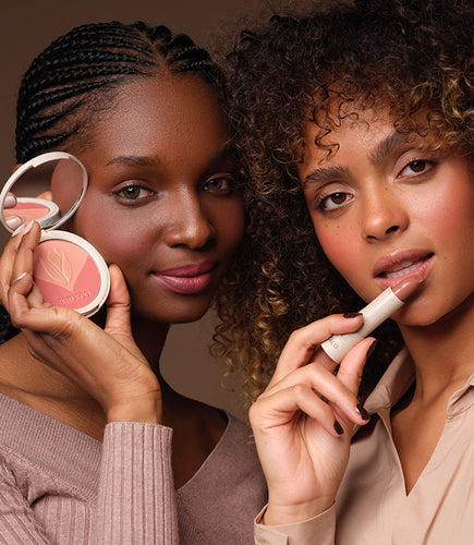 Zwei Frauen halten Make-up Produkte vor ihr Gesicht