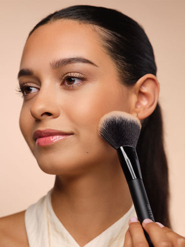 Model trägt Bronzer mit fluffigen Puderpinsel auf