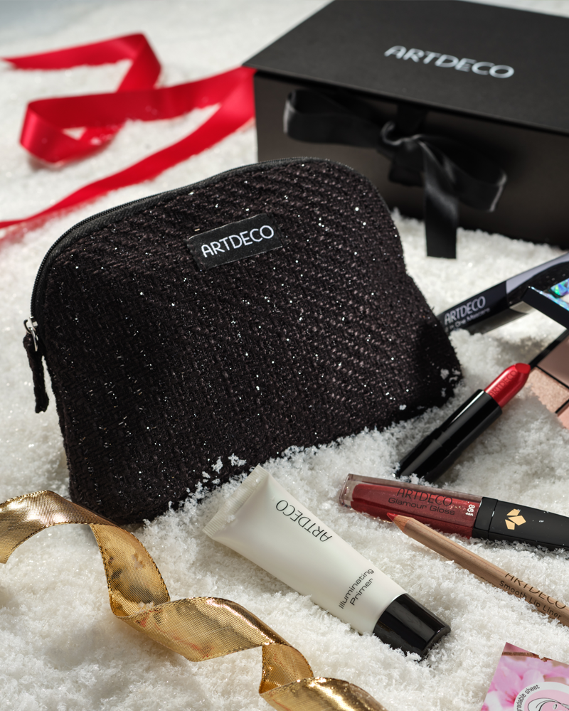 Mood-Bild mit einer Kosmetik Tasche und der ARTDECO Box im Schnee umgebenen von verschiedenen Make-up Produkten