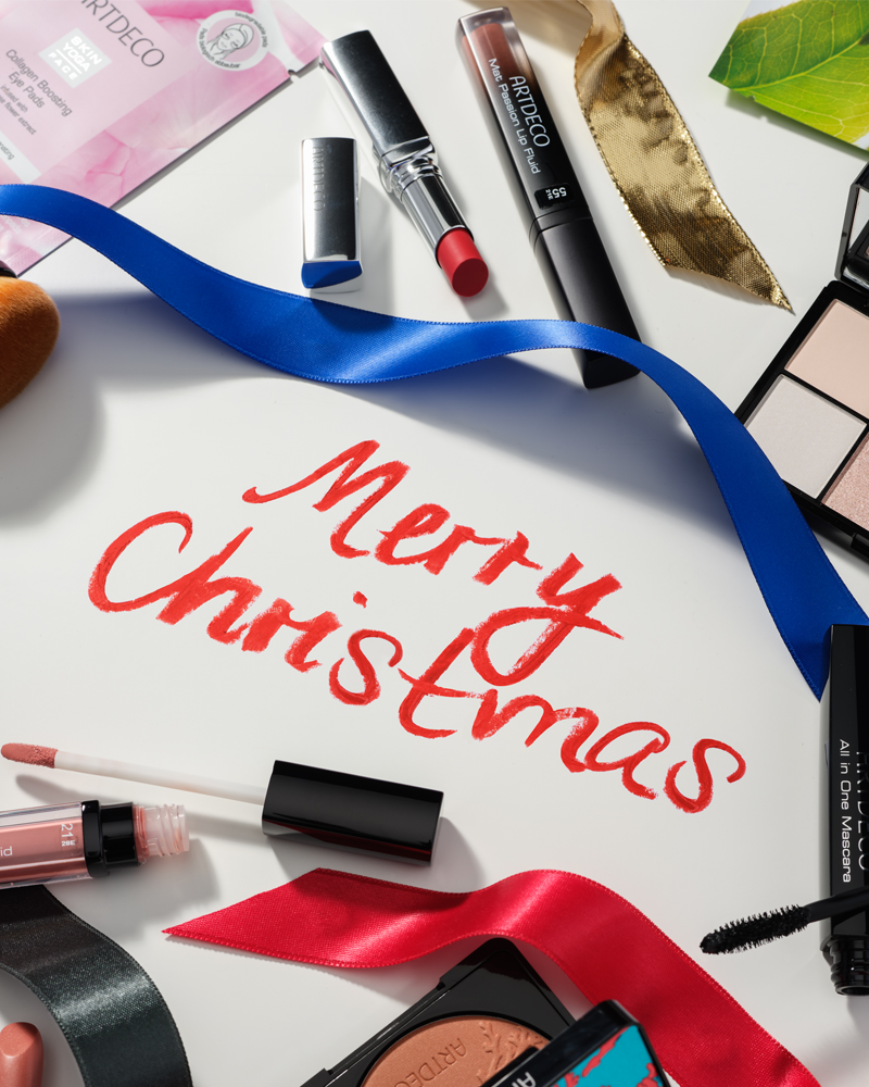 Mood-Bild mit verschiedenen Artdeco Make-up Produkten die das Wort „Merry Christmas“ umgeben