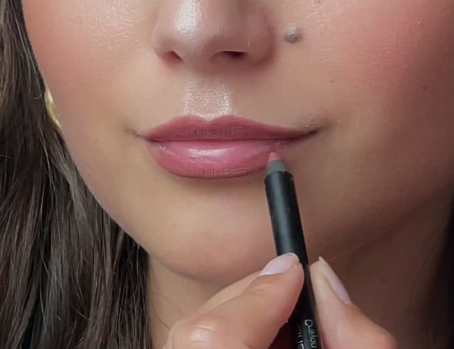 Model konturiert die Lippen mit einem Lipliner in warmem Rosébraun.