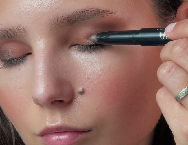 Model trägt hellen Cream-Lidschatten in schimmerndem Braun auf das bewegliche Lid.