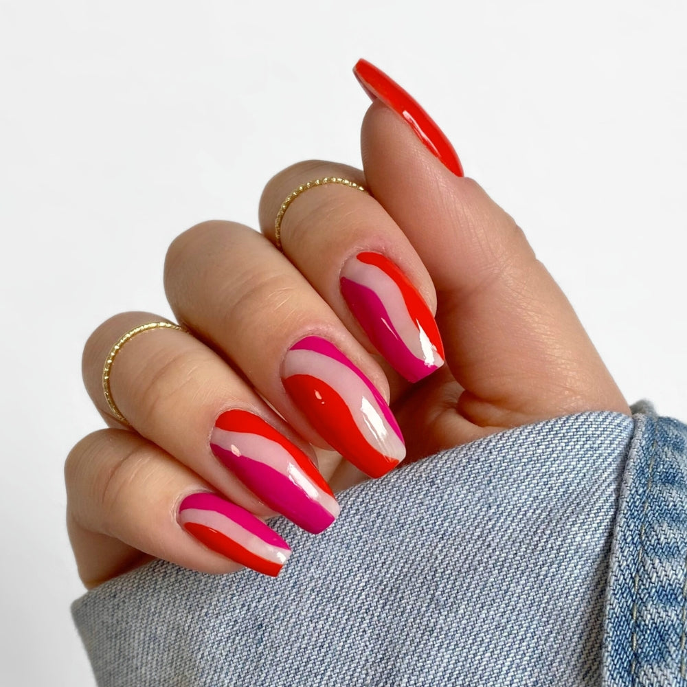 Fertiges Nagel Design mit rotem und pinkem Wellen Muster in einer Jeansjacke