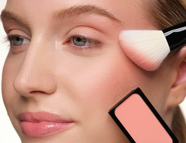 Close-up auf die Wange des Models, auf welcher ein pinker Blush mit einem Blusher Brush aufgetragen wird