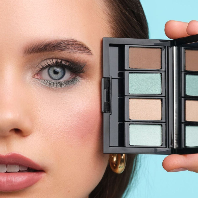 Model mit blauen Augen hält eine Beauty Box Quattro mit passenden Lidschatten für blaue Augen nah an ihre Augen.