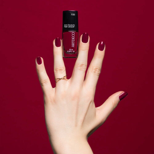 Dunkelrot lackierte Nägel auf dunkelrotem Hintergrund und dem Art Couture Nail Lacquer in N°705 - berry.