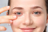 Eine weibliche Person trägt sich eine Creme unter den Augen auf