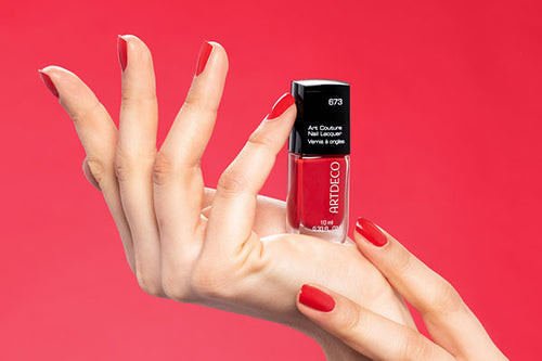 Es wird eine Hand gezeigt auf der ein roter Nagellack präsentiert wird