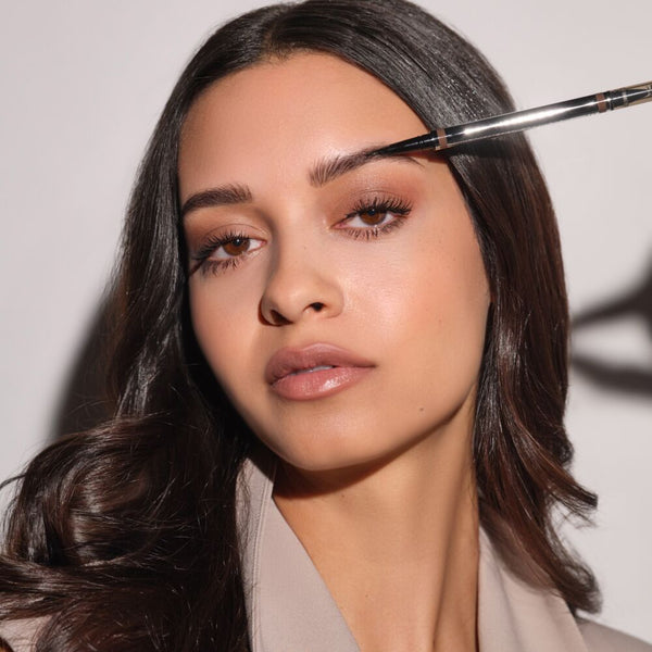 Braunhaariges Model trägt den 24h Micro Brow Liquid Liner auf die Augenbraue aus