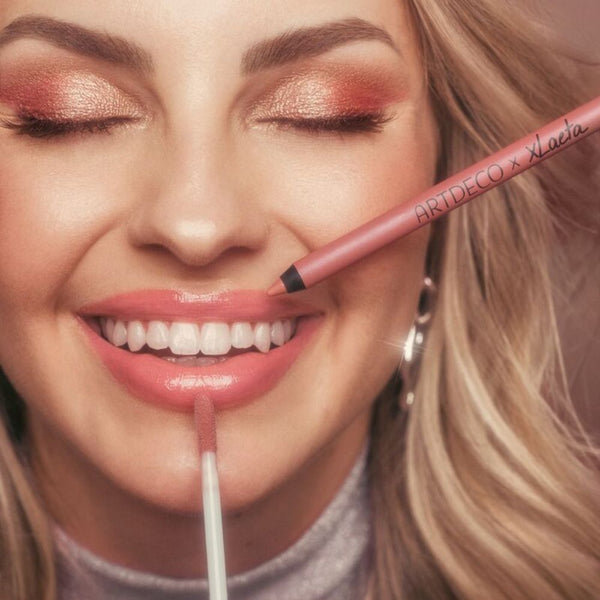 Blondes Model lacht, während der Lip Liner und das Plumping Lip Fluid aus dem limitierten I'm your Lip Kit tonight auf die Lippen aufgetragen werden