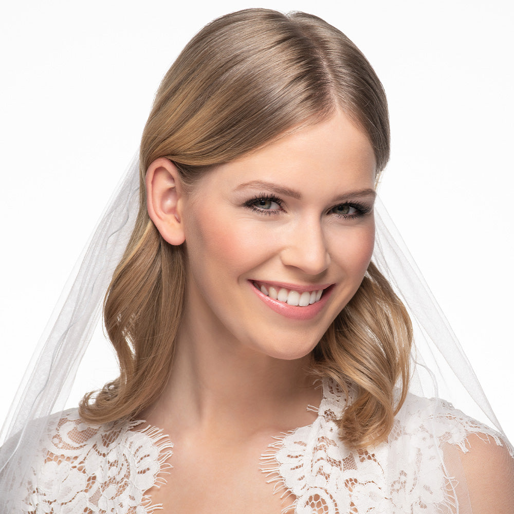 Foto in Profil-Ansicht eines Models mit weißem Schleier und Brautkleid - lächelnd.