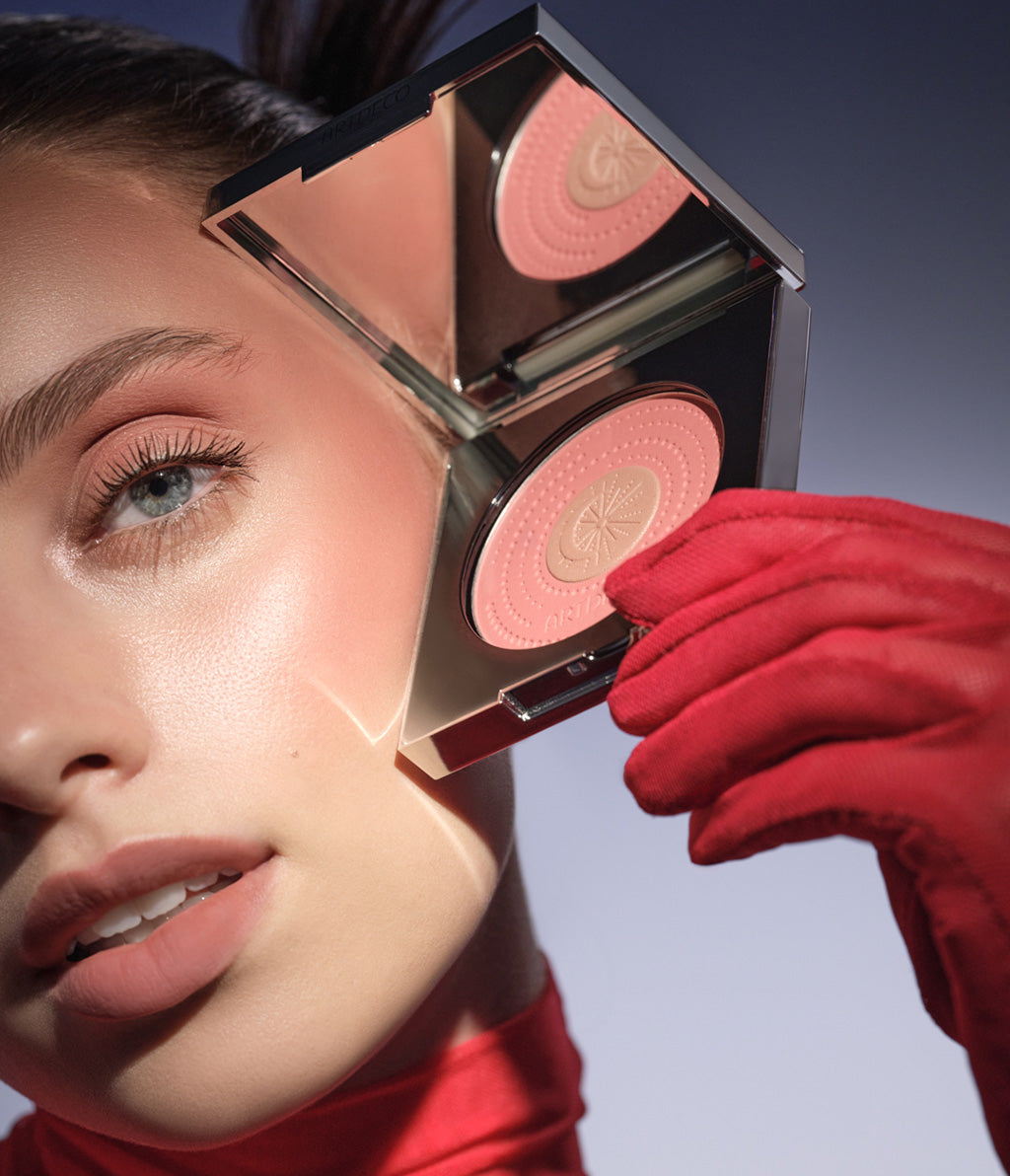 Model hält den limitierten Galactic Blush Couture, in der Hand neben ihrem bereits mit dem Blush geschminkten Teint.