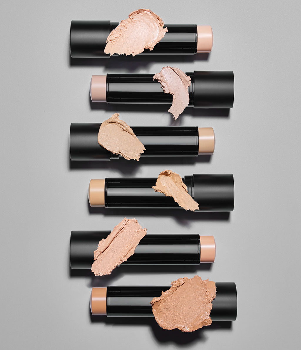Alle sechs Skin Perfecting Face Sticks liegen aufgereiht auf einem grauen Hintergrund. Der jeweilige Texturswatch liegt über dem dazugehörigen Stick.