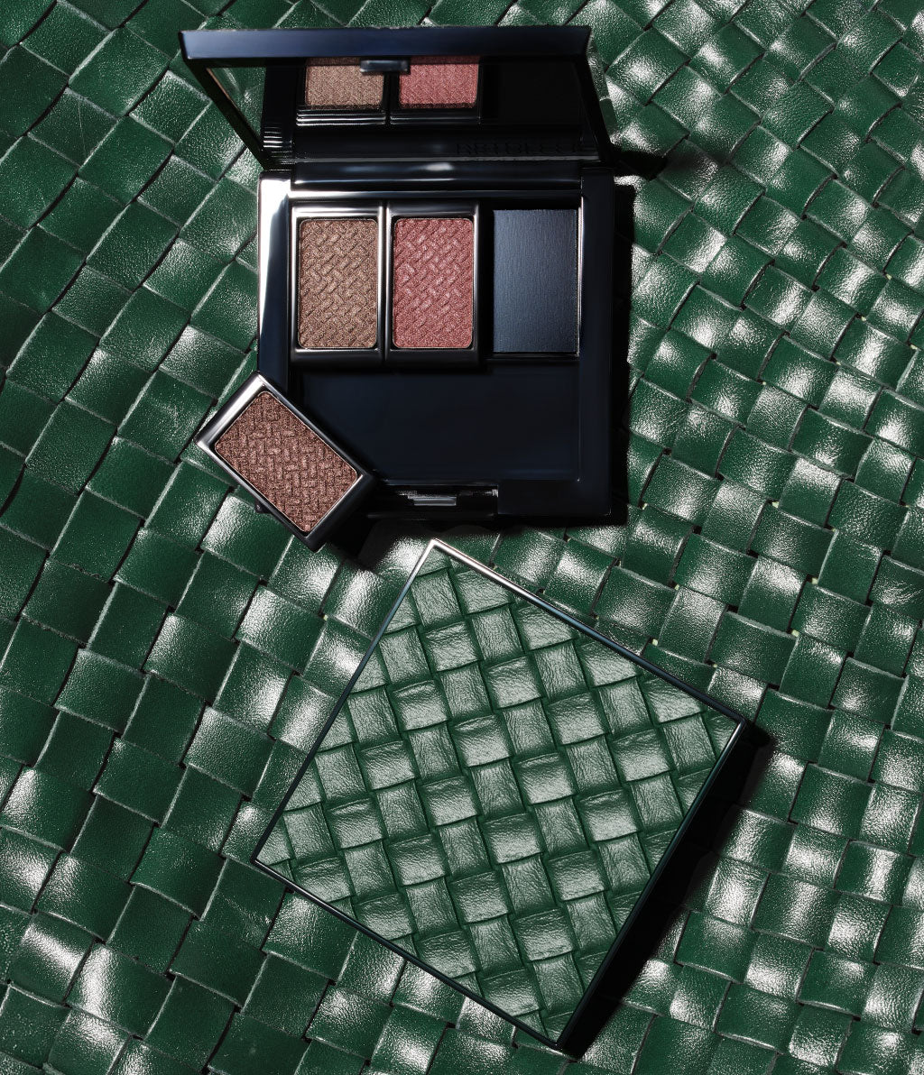 Limitierte Beauty Box mit Intrecciato-Design, liegt auf einem Hintergrund im selben Design und gefüllt mit den drei Lidschatten aus der Kollektion.