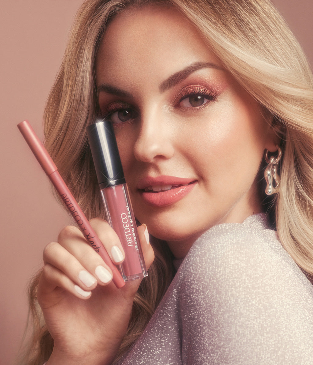 Eine lächelnde Frau mit sanftem Make-up, die das Lip Kit mit Plumping Lip Fluid und Soft Lip Liner präsentiert