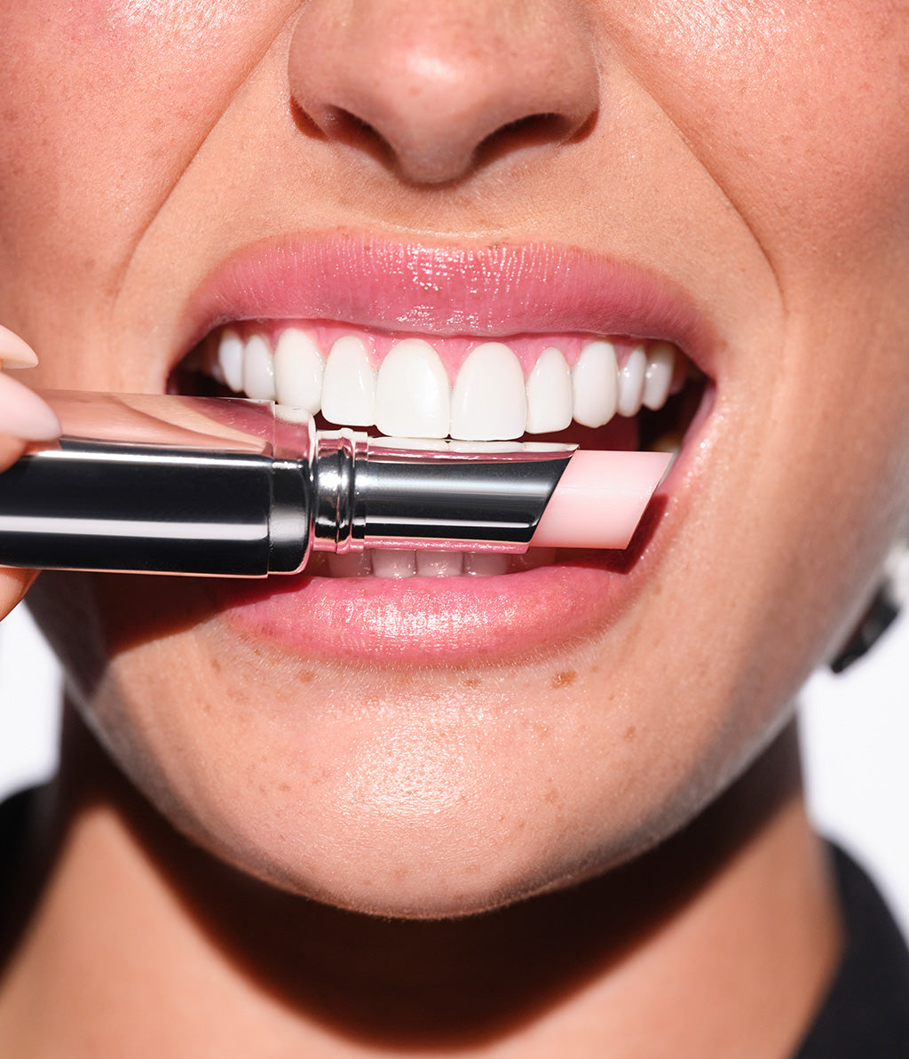 Close-up auf den Mund des Model, das den mit dem Color Booster Lip Balm zwischen den Zähen posiert
