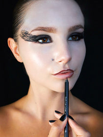 Model mit fast fertig geschminkten Halloween-Make-up trägt einen dunklen Lipliner auf