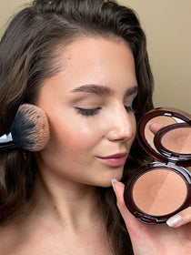 Bronzing Puder wird mit einem fluffigen Puder-Pinsel seitlich auf die Wange aufgetragen, um einen Sonnengeküssten Look zu zaubern