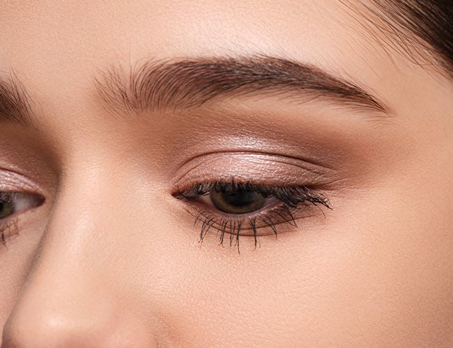 Es wird ein geschminktes Auge mit violettem Lidschatten gezeigt