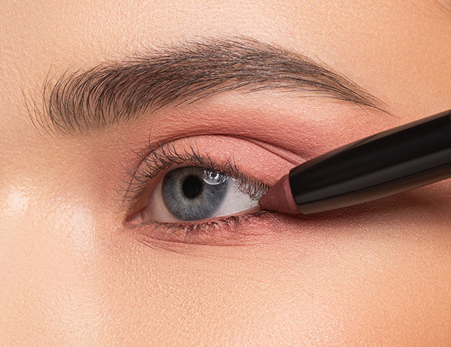 Ein dunklerer Lidschatten-Stift wird auf der Wasserlinie aufgetragen um den Augen-Look zu intensivieren