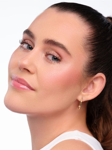 Model mit natürlichem Clean Girl Make Up Look schaut seitlich über ihre Schulter.
