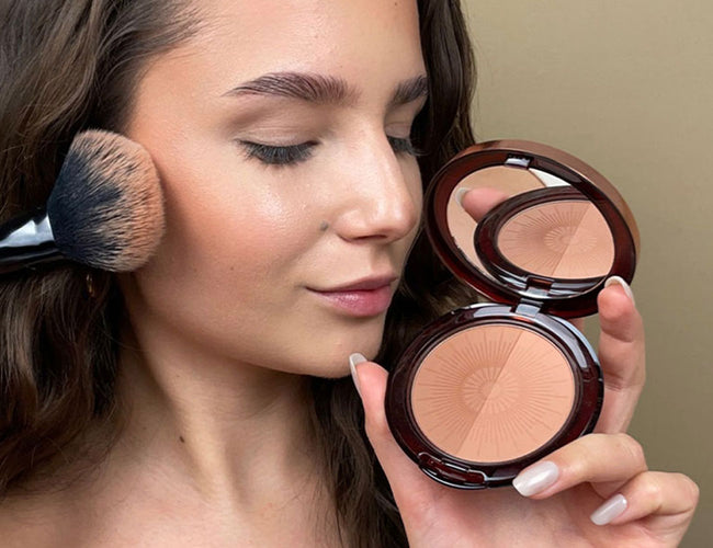 Bronzing Puder wird mit einem fluffigen Puder-Pinsel seitlich auf die Wange aufgetragen, um einen Sonnengeküssten Look zu zaubern