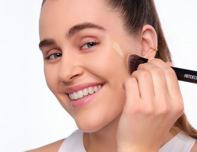 Model trägt die Perfect Matte Serum Foundation​ mit dem ARTDECO Face Brush auf die Wangenpartie auf.