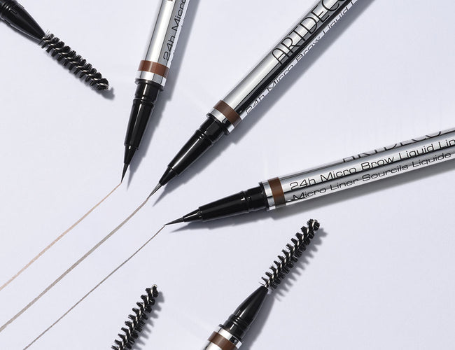 Drei Farben des 24h Micro Brow Liquid Liners platziert auf weißem Hintergrund mit gezeichneten Swatch-Linien.
