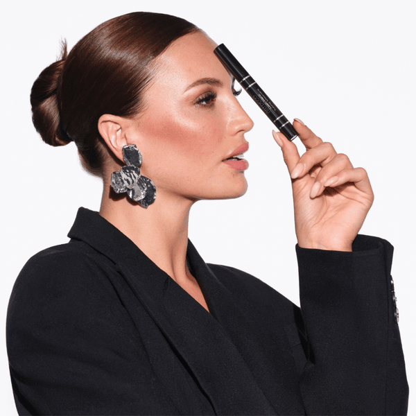 Model hält sich die Lash Hero Tubing Mascara an die Stirn.