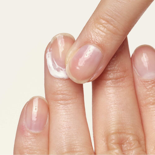 Eine Nagelhautcreme wird auf einem Finger aufgetragen. 