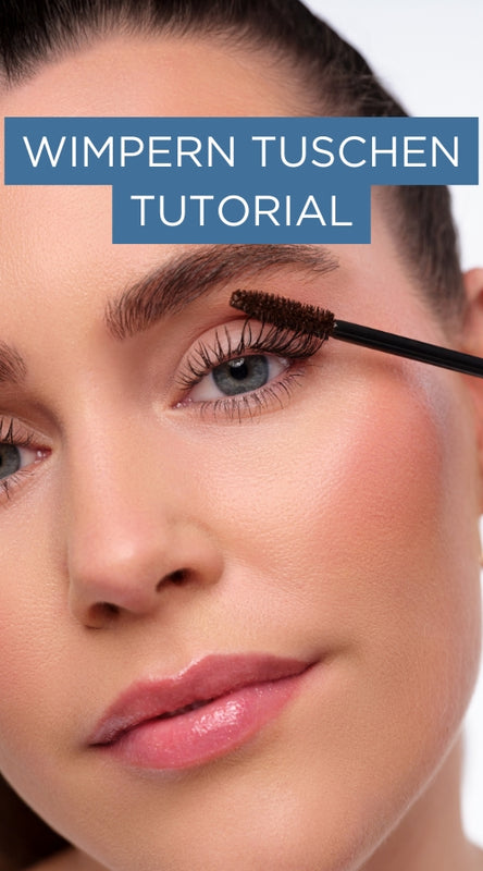 Model tuscht die oberen Wimpern. Schriftzug „Wimpern tuschen Tutorial“ weist auf verlinkte Schminkanleitung hin.