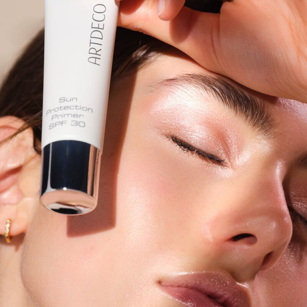 Model hält den Sun Protection Primer SPF 30 vor an ihrem Gesicht.