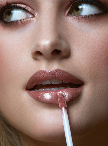 Model mit Glamour Make-up trägt glamourösen Lipgloss auf die Lippen