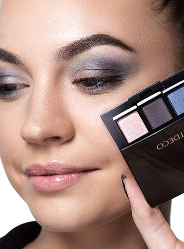 Ein Model hält eine Lidschattenpalette neben ihr fertiges Augen Make-up.