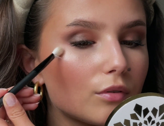 Model setzt mit Highlighter zarte Lichtakzente auf den Wangenknochen.