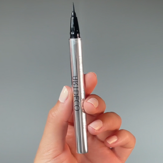 Eyeliner wird vor die Kamera gehalten.