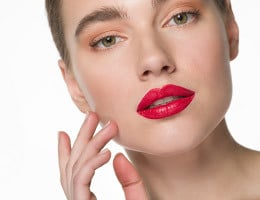 Frau mit voluminösen Lippen trägt einen roten Lippenstift