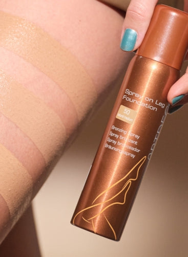 Eine Dose der Spray On Leg Foundation wird an ein Bein gehalten, auf dem drei Farben des Bein Make-Ups aufgetragen sind.