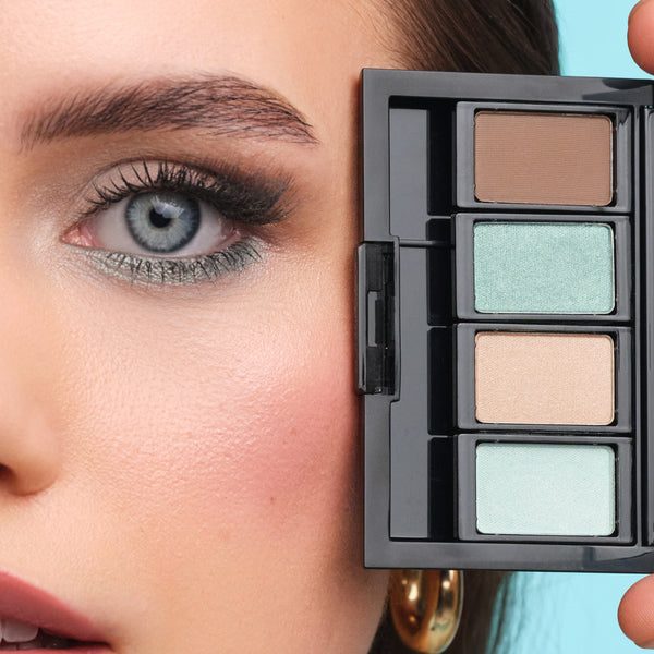 Model mit blauen Augen hält eine Beauty Box Quattro mit passenden Lidschatten für blaue Augen nah an ihre Augen.