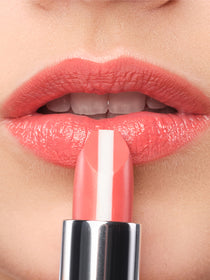 Ein korall-farbener Lippenstift wird an geschminkte Lippen gehalten