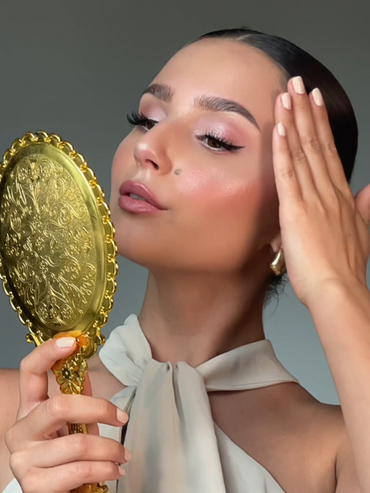 Geschminktes Model schaut sich in einem Spiegel an.