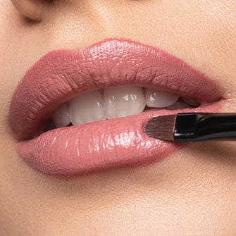Close-up auf Nudefarbene Lippen auf die eine Lippenstift mit einem Pinsel aufgetragen wird
