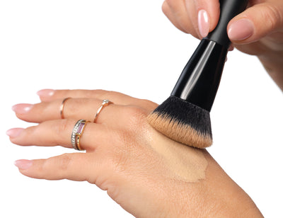 Foundation wird mit einem Pinsel auf dem Handrücken aufgetragen, um sie anzuwärmen und optimal für das Auftragen vorzubereiten. 