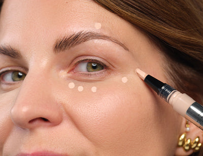 Concealer wird punktuell unter dem Auge und am äußeren Augenwinkel aufgetragen, um die richtige Auftragetechnik zu zeigen.